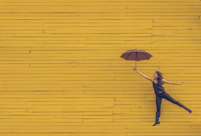 Brain Power: Woman appearing to fly against a wall using umbrella