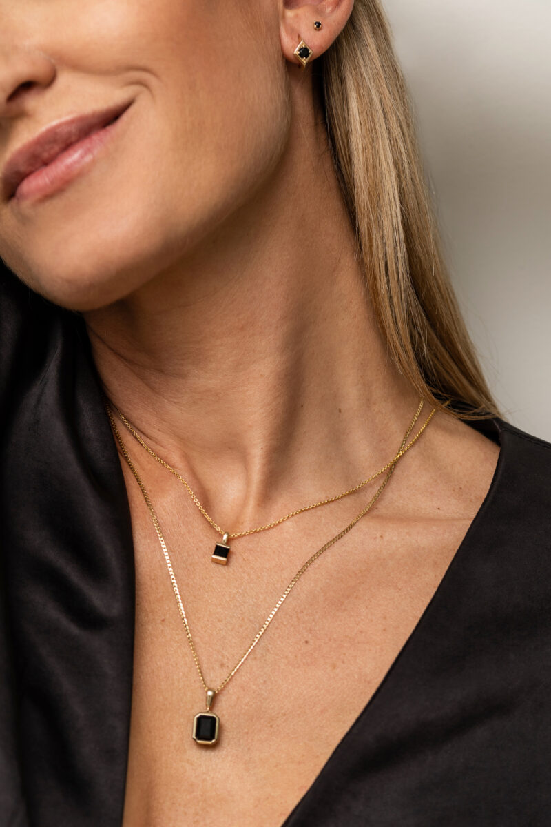 Caroline Elie showing two gold and onyx necklaces