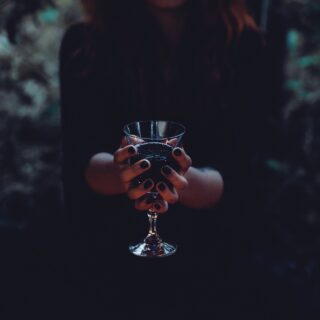 Best Halloween Items: Woman in Witches Costume holding a wine goblet