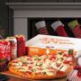 Pizza Pizza: Santa reaching for a slice of pizza on a table near a Christmas tree