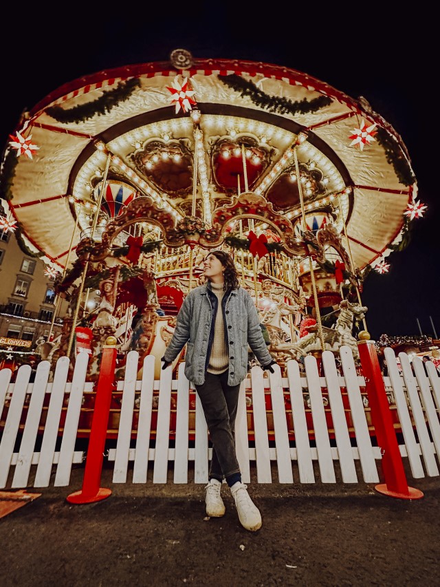 Holiday Photos: Woman in front of a holiday themed Merry-Go-Round