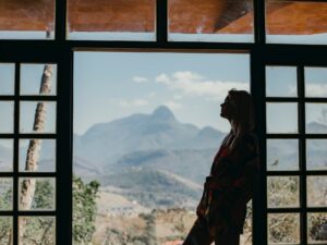 Coping with Anxiety: Woman standing at windows looking out onto a mountain