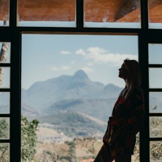 Coping with Anxiety: Woman standing at windows looking out onto a mountain