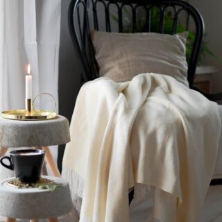Hygge: Chair with a blanket and candle on a side table
