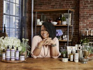 Lisa Price: Lisa leaning over a bar with Carol's Daughter products surrounding her