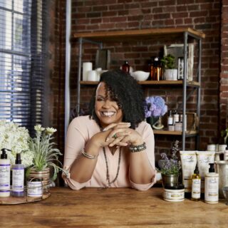 Lisa Price: Lisa leaning over a bar with Carol's Daughter products surrounding her