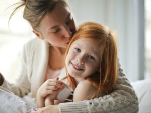 Set your kids up for success: Mother kissing her daughter on the head