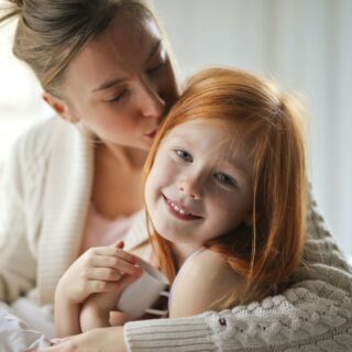 Set your kids up for success: Mother kissing her daughter on the head