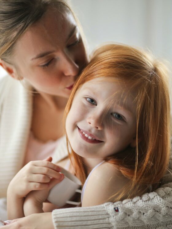 Set your kids up for success: Mother kissing her daughter on the head