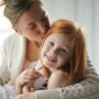 Set your kids up for success: Mother kissing her daughter on the head
