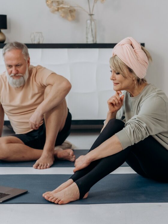 Golden Years: Man and woman sitting on yoga mats looking at a laptop