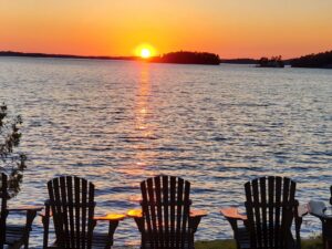 Muskoka: Muskoka chairs facing lake at sunset