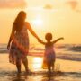 Mother's Day Gift Ideas: Mother and child walking hand in hand along the beach at sunset