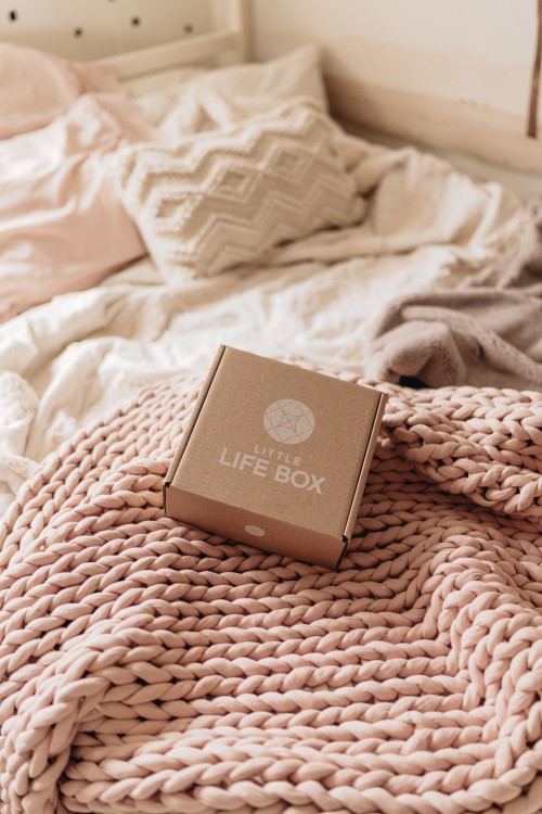 Canadian Brands: Little Life Box on a bed surrounded by blankets and afgans in neutral colours