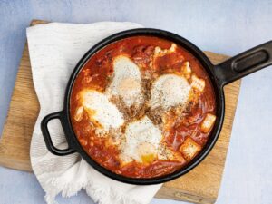 Shakshuka: Shakshuka in a pan on a cutting board
