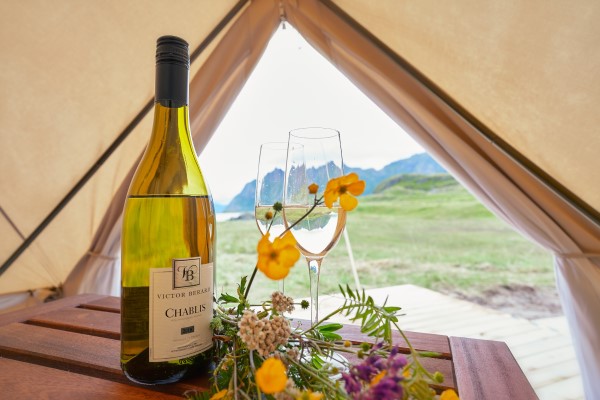 Glamping: View from inside a te4nt with a wine bottle and glasses in the foreground