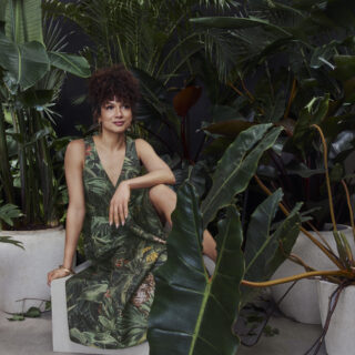 Toni Fifi x Reitmans: Toni Fifi sitting down in a green printed dress among greenery