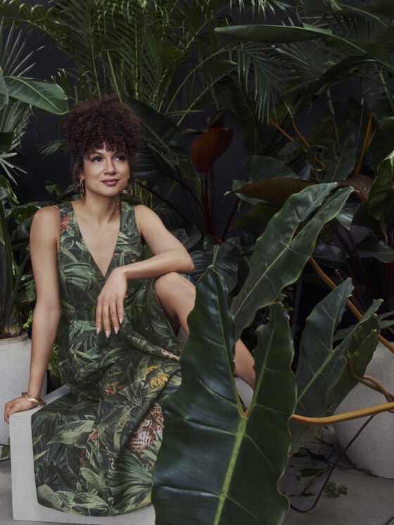 Toni Fifi x Reitmans: Toni Fifi sitting down in a green printed dress among greenery