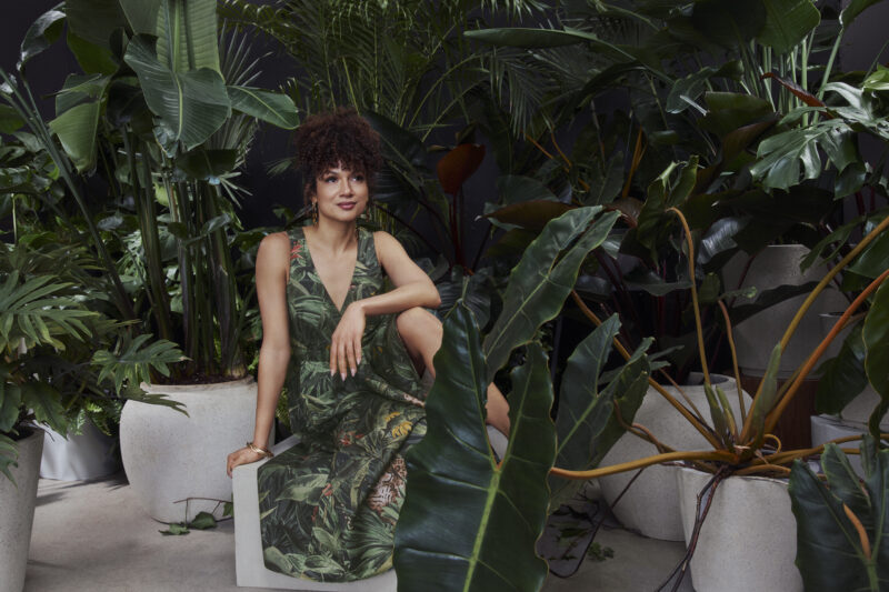 Toni Fifi x Reitmans: Toni Fifi sitting down in a green printed dress among greenery