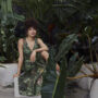 Toni Fifi x Reitmans: Toni Fifi sitting down in a green printed dress among greenery