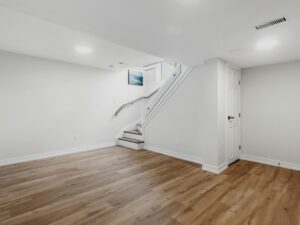 Basement Waterproofing: Empty basement area with hardword floors and a staircase