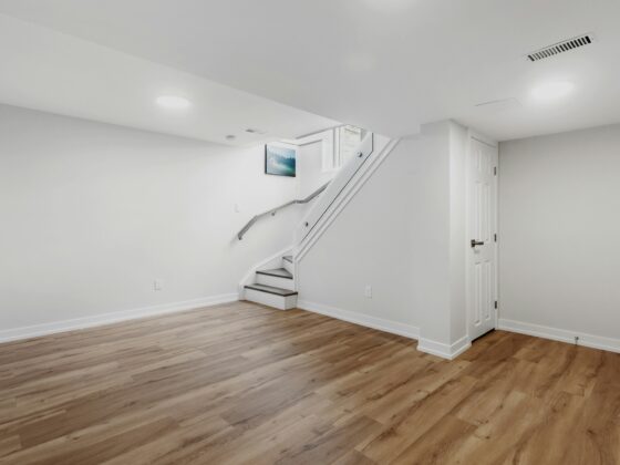 Basement Waterproofing: Empty basement area with hardword floors and a staircase