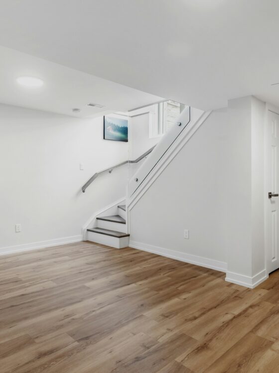 Basement Waterproofing: Empty basement area with hardword floors and a staircase