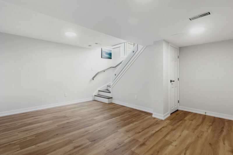Basement Waterproofing: Empty basement area with hardword floors and a staircase