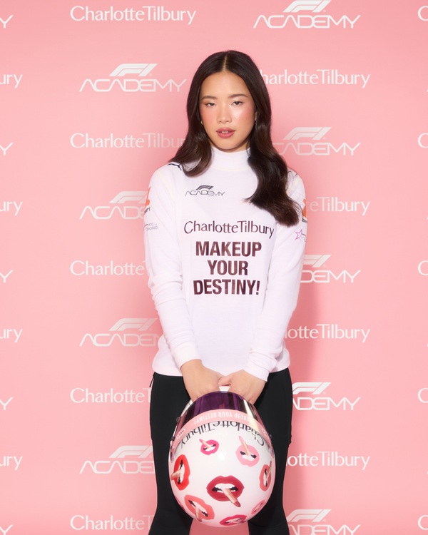 F1 Academy: Chloe Chong holding a helmet in front of a step and repeat