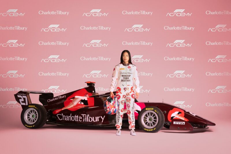 F1 Academy: Charlotte Tilbury emblazoned F1 racing car with Chloe Chong standing in front of it and a step and repeat