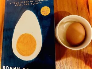 How to Share an Egg: Copy of the book next to a small dish with a hard-boiled egg