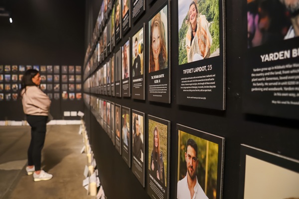 Nova Music Festival Exhibition: Woman looking at wall of photos of those who lost their lives at the Nova Festival