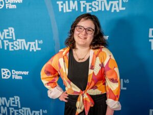 The Latest With Maya: Maya Abrahamsson in front of a step and repeat
