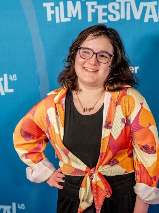 The Latest With Maya: Maya Abrahamsson in front of a step and repeat