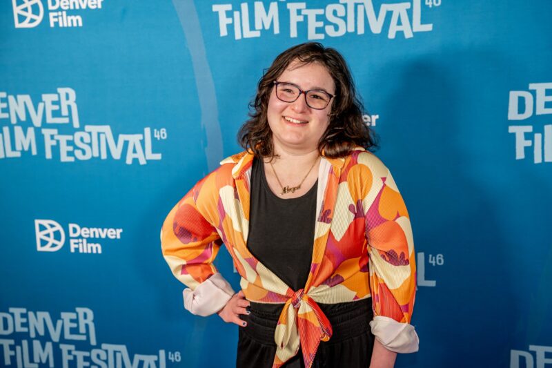 The Latest With Maya: Maya Abrahamsson in front of a step and repeat
