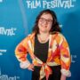 The Latest With Maya: Maya Abrahamsson in front of a step and repeat