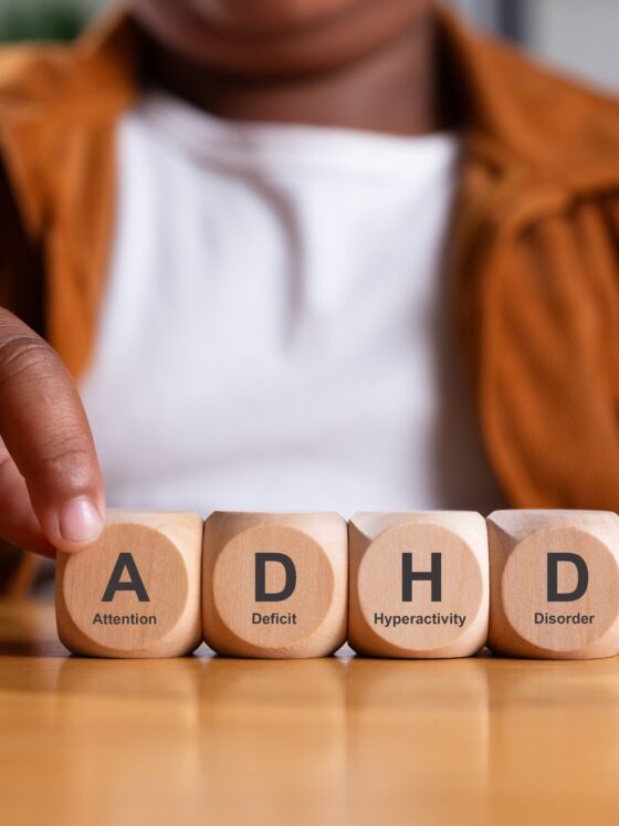 Fine Motor Skills in Kids with ADHD: Hand of black boy puts wooden cube with ADHD, Attention Deficit Hyperactivity Disorder on table.