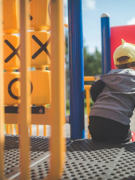 Jungle Gym: Little boy sitting on a jungle gym in close up shot