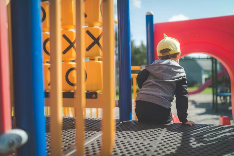 Jungle Gym: Little boy sitting on a jungle gym in close up shot
