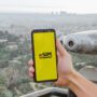 eSim: Hand holding a cell phone with eSim on the screen against a city view background