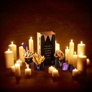 Meal of Misfortune: Wendy's x Wednesday full meal including chicken nuggets, fries, Frosty and themed paper bag amongst candles