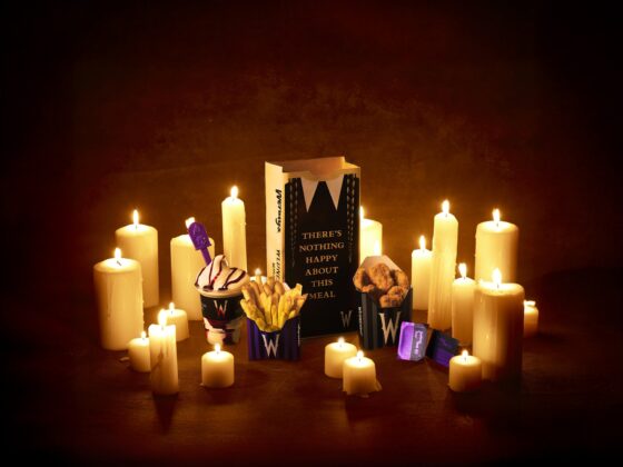 Meal of Misfortune: Wendy's x Wednesday full meal including chicken nuggets, fries, Frosty and themed paper bag amongst candles