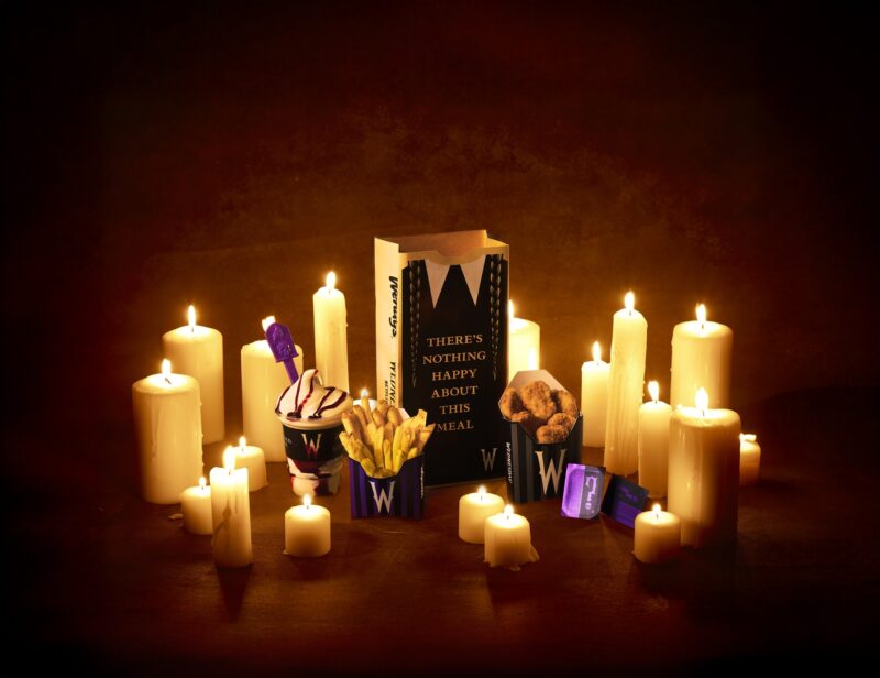 Meal of Misfortune: Wendy's x Wednesday full meal including chicken nuggets, fries, Frosty and themed paper bag amongst candles