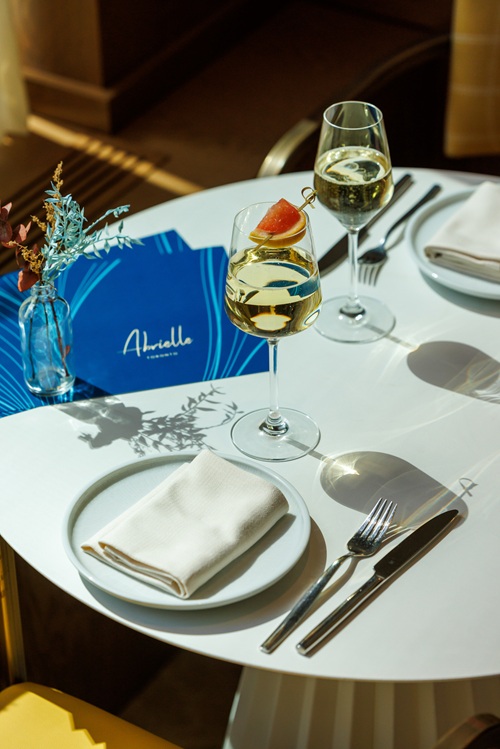 Abrielle: Dining table set with plates and cutlery with menus and two glasses of white wine