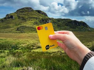 eq bank card: Woman's hand holding an EQ Bank Card in front of a hill