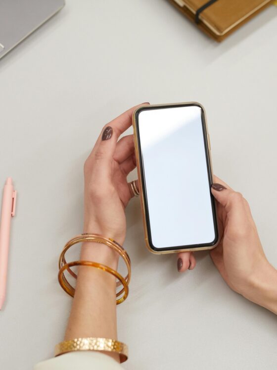 Digital Declutter: Woman's hand holding a smartphone in front of her laptop