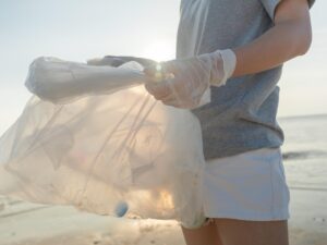 Volunteering: woman holding a bag full of plastic bottles on the beach