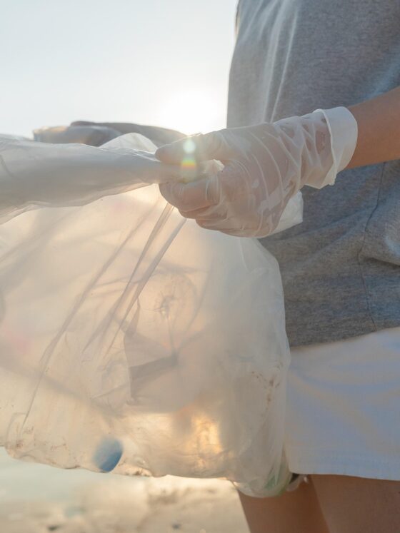 Volunteering: woman holding a bag full of plastic bottles on the beach