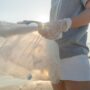 Volunteering: woman holding a bag full of plastic bottles on the beach