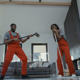 Cleaning Business: Man and woman cleaning in orange jumpsuits and playfully smiling at one another